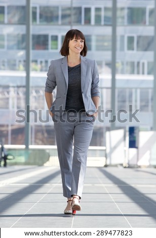 Full length portrait of a relaxed business woman smiling and walking