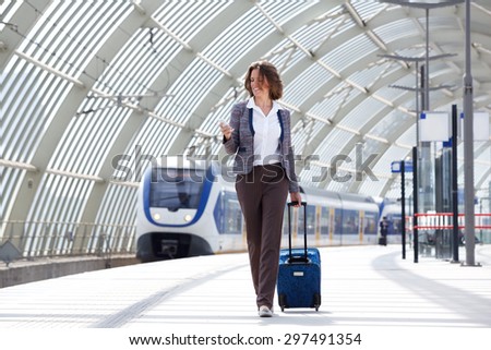 Full length portrait of a traveling business woman walking with bag and phone