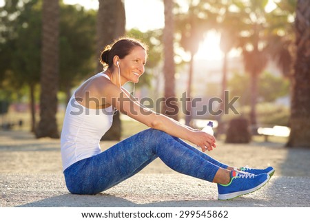 Portrait of a sports woman sitting outside smiling after workout