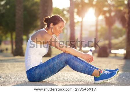 Portrait of a tired sports woman sitting outside after workout exercise with bottle a of water
