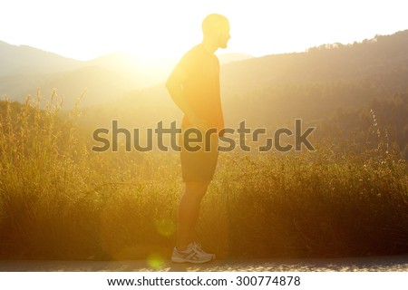 Side portrait of a silhouette male jogger standing outside in nature