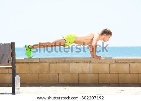 Young fitness man push up workout outside by the sea