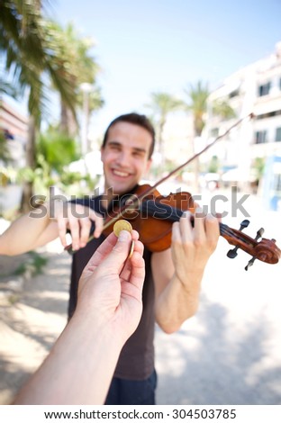 Hand paying money to busker man playing violin outside