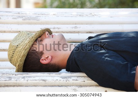 Side portrait of a man sleeping on park bench outside
