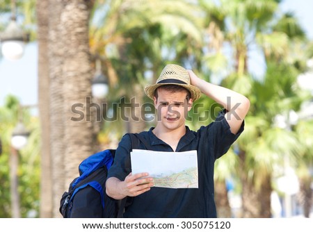 Portrait of a lost tourist with bag holding map