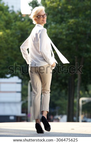 Full body portrait of a confident young woman walking away -from behind