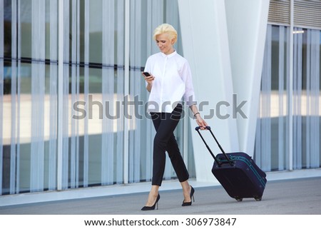 Full body business woman traveling with suitcase and mobile phone
