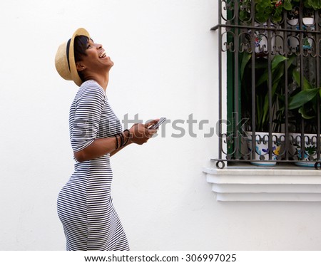 Profile portrait of a laughing young woman walking with mobile phone