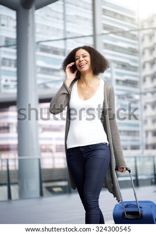 Portrait of a traveling young african american woman walking and talking on cellphone