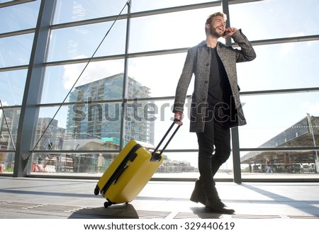 Side portrait of a smiling travel man walking and talking on mobile phone