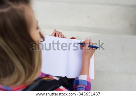 Portrait from top of a young woman writing a to do list in book