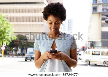 Portrait of young black woman listening to music on her cell phone outside in the city