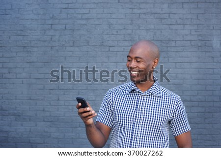 Close up portrait of smiling african man looking at mobile phone