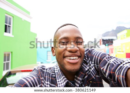 Close up of happy young man on the city street taking a self portrait