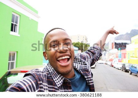 Close up of excited young african guy out on the city street taking a self portrait