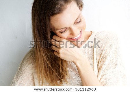 Close up candid portrait of a woman laughing against white background