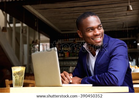 Portrait of a smiling black businessman with laptop at cafe
