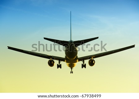Large commercial airplane flying overhead landing with the sunset light in the background
