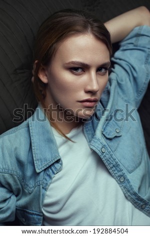 Beauty portrait of a young model in a denim shirt posing lying on back. Red hair.