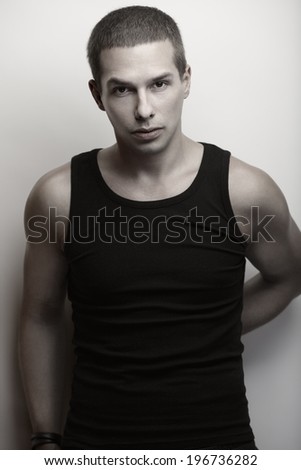 Handsome man in black tank top posing against white background.