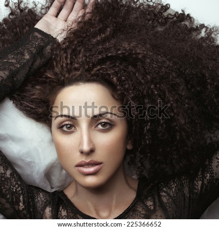 Sensual fashion portrait of a beauty brunette girl with curly hair.