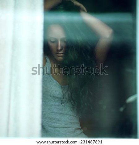Sensual portrait of a beauty brunette model behind the window.