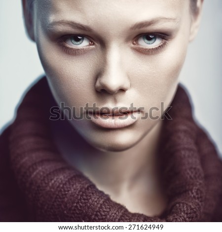 Closeup beauty portrait of a serious blonde girl in brown roll neck jumper.