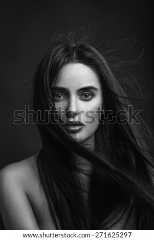 Beauty portrait of a young beautiful brunette girl with long black straight flying hair. Magnificent hair. Black and white