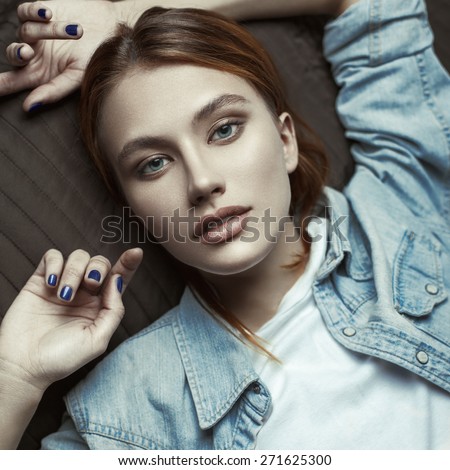 Fashion beauty portrait of young red-haired model with straight hair in denim shirt.
