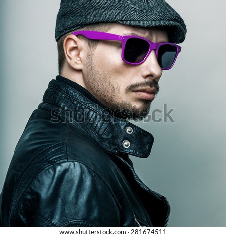 Fashion portrait of young handsome brutal bearded man in leather jacket and sunglasses.
