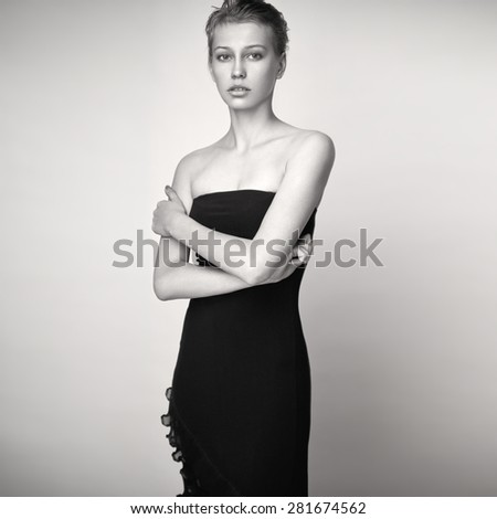Fashion portrait of a young pretty blonde girl in black dress. Black and white.