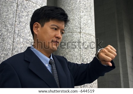 Asian Man in A Business Suit Looking At The Time
