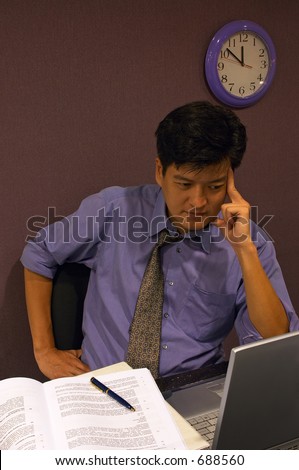 Working On A Solution - An employee working late into the night thinking hard for a solution