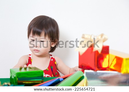 Cute little asian girl interesting wrap  a beautiful gift box on table, on white background