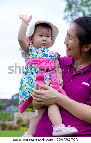 Happy asian woman and cute little girl relaxing at home back yard and bright sky background, mother carrying  her daughter