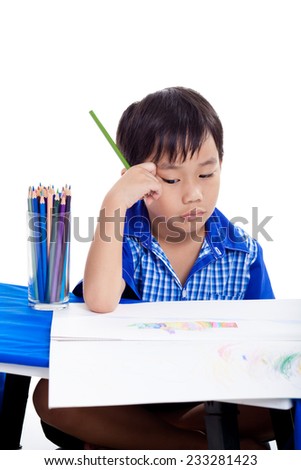 Asian boy thinking and boring emotion at the table with images paper and colour pencils , isolated on white background