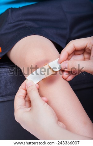 Closeup of child knee with a plaster (for wounds) and bruise, Mother provides first-aid