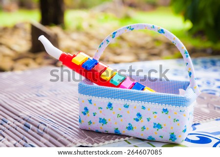 Plastic toy music pipe in basket prepared for kids at backyard (Child Development and Learning)