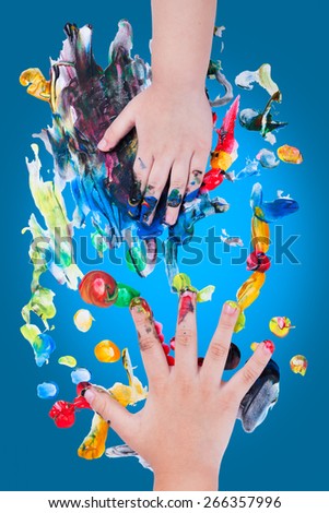 Closeup of little children hands doing finger painting with various colors on blue background, art education and creativity concept, top view