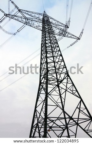 A high voltage electricity pylon in front of the gray sky in early winter.