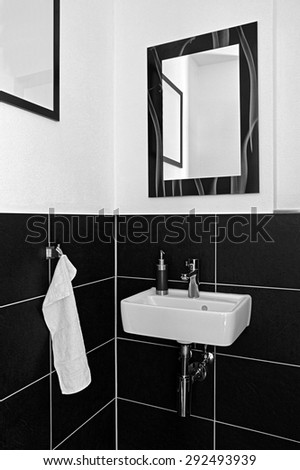 A modern bathroom sink and mirror with hand towel, held in black an white.