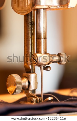 Closeup of a needle of a sewing machine that is sewing a textile or cloth or fabric
