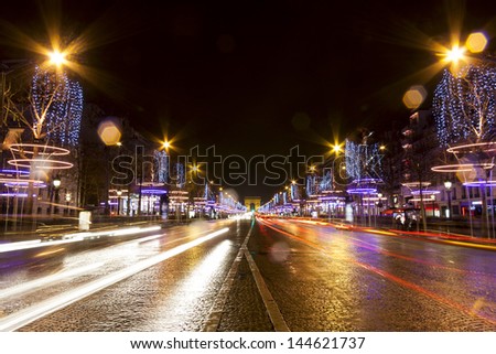 Decorated Champs-Elysees street with light trails at night in Paris, France