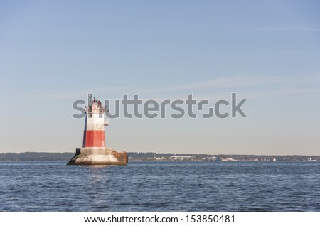 Big white and red colored marine sign or beacon or lighthouse in sea. Bird sit on top of the lighthouse.