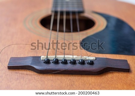 Close up of brown guitar with torn string