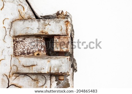 Rusty and old metal hinge of crematory door with white cement wall
