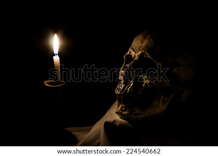 Halloween image with human skull and burning candle