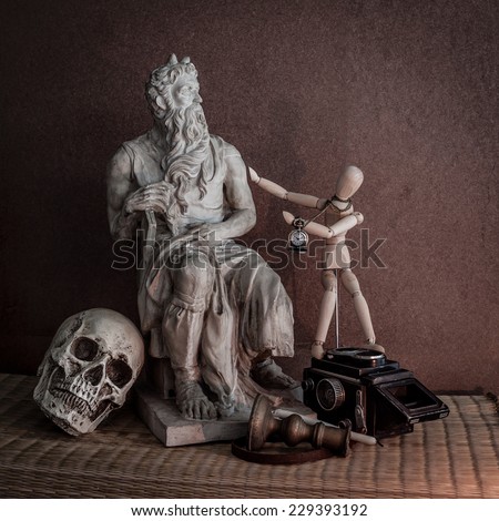 Still life of moses statue ,skull,wooden figure on mat with wooden brow background