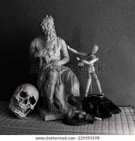 Still life of moses statue ,skull,wooden figure on mat with wooden background