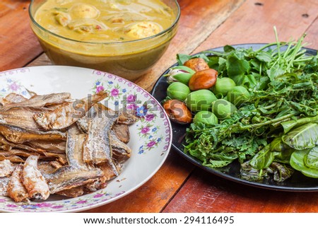Fried fish ,curry egg with coconut milk and fresh vegetable in plate on wooden table